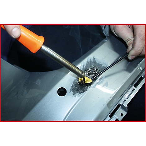 Reparatur eines Stoßfängers mit einem Lötkolben. Grauer Stoßfänger, Hand mit Lötkolben, gelbes Reparaturwerkzeug.